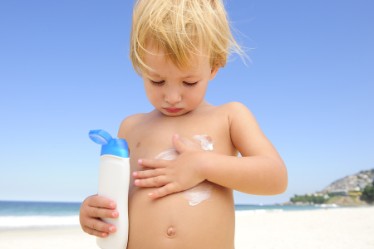 Boy applying sunscreen on body