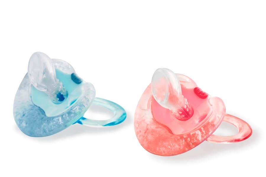 Pink and blue pacifiers against white background