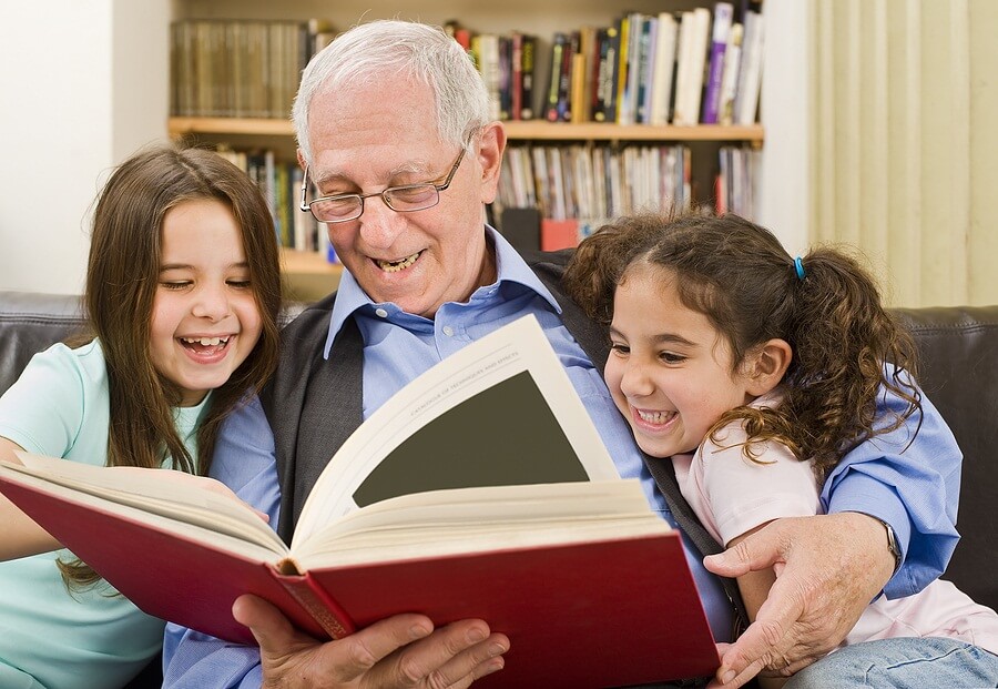 Senior reading a book to two children