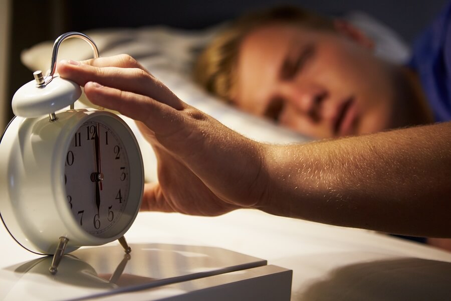 Alarm clock on night stand getting turned off by teen
