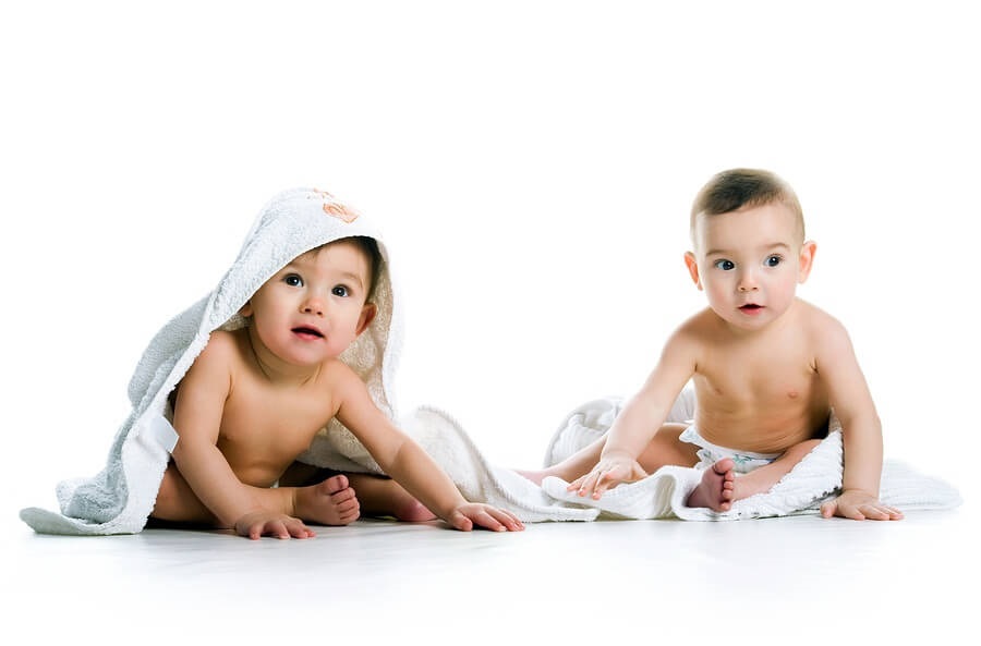 Twin boys in towels against white background